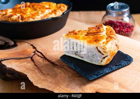 Food concept homemade pork pie or meat pie on stone plate and cast Iron Skillet on wooden background Stock Photo