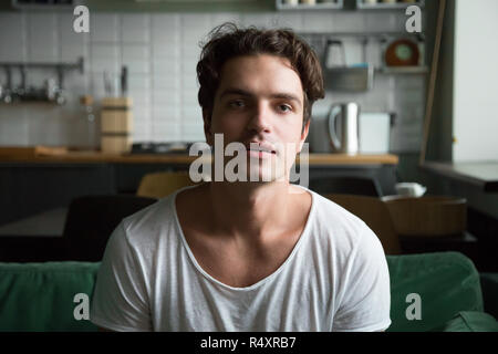 Handsome young man sitting on couch looking at camera Stock Photo