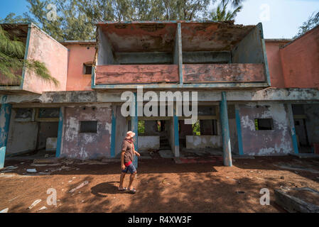 A tiorist explores the abandoned buildings of Santa Carolina Hotel on Paradise iIsland in MOzambique's Bazaruto Archipelago. Stock Photo