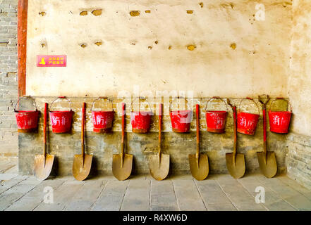 Eight fire buckets with shovels  hung on a brown wall in Pingyao, China Stock Photo