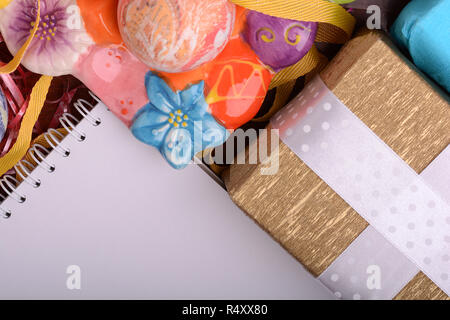 Arrangement of Gift Boxes in Wrapping Paper with Checkered Ribbons and Decorated Easter Eggs. White paper notepad Stock Photo