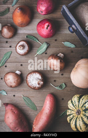 A scene of autumn produce including pears, squash, sweet potatoes and sage on a wood background.