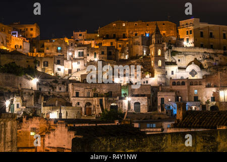 Night view of the old city of Matera, Italy, with it's abandoned hillside homes, church spires and ancient dwellings lit up in the evening. Stock Photo