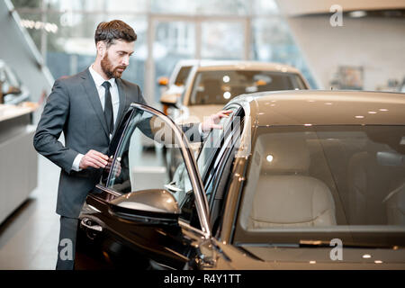 Elegant businessman choosing new luxury car looking at the car intreior in the showroom Stock Photo