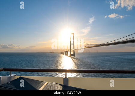 View of the setting sun over the Öresund Bridge which spans the strait between Sweden and Denmark from a boat on the Baltic Sea. Stock Photo