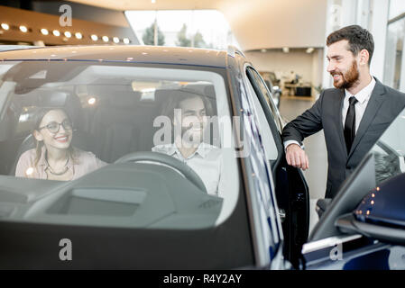 Salesperson with couple choosing a new car in the showroom Stock Photo