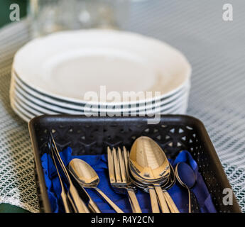 Closup view of Shining Cutlery on the Blue Napkin, with White Plates in the Background Stock Photo