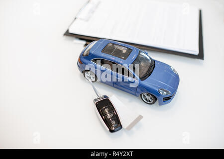 Close-up of a toy car with keychain and documents on the white table Stock Photo