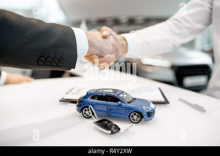 Close-up of a handshake at the table with toy car and keys. Car buying concept Stock Photo