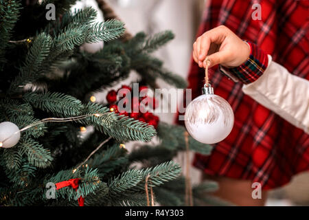 Little child's hand decorating Christmas tree indoors. Stock Photo