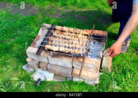 Appetizing shashlik outside. Cooking of pork meat. Barbecue lunch outdoors. Process of cooking pork meat on fire. Shashlik prepared on barbecue grill  Stock Photo