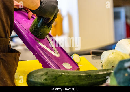 Male Chef Cutting Eggplant in the Kitchen - with Glove on his Hand Stock Photo