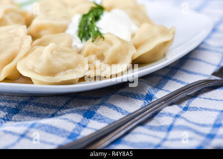 Hot dumplings with sour cream and dill. Close up Stock Photo
