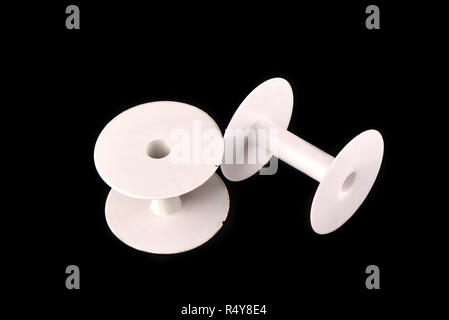 Two plastic empty spools of thread on a black background Stock Photo