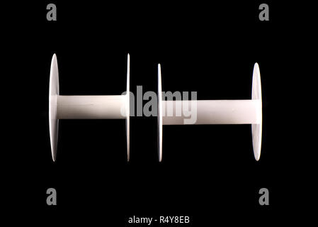 Two plastic empty spools of tape or strips of cloth on a black b Stock Photo
