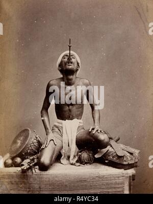 Photograph of an Indian juggler performing the sword-swallowing trick, Madras. A performance or trick. . Juggler performing the sword-swallowing trick, Madras. Probably shown at the Vienna Exhibition of 1873. Studio portrait of juggler, with only the hilt of his sword protruding from his mouth. Source: Photo 1000/52 4964. Stock Photo