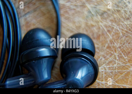Close-up headphone stack on table, modern smartphone's earbuds device accessories. Stock Photo