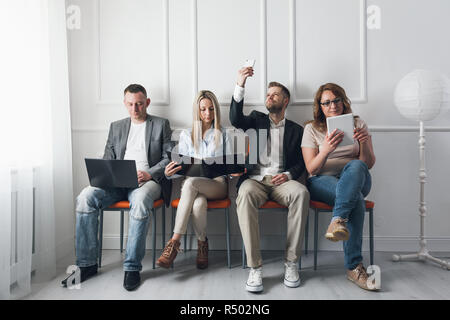 Group of creative people sitting on chairs in waiting room Stock Photo