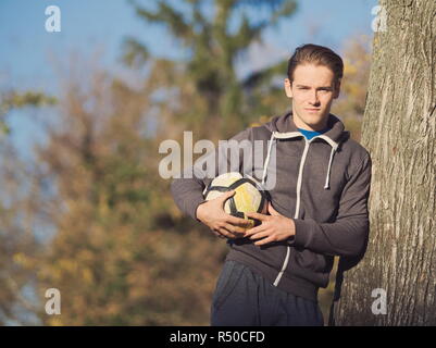 Soccer Player Posing with Football in the Park on a Sunny Autumn Day Stock Photo