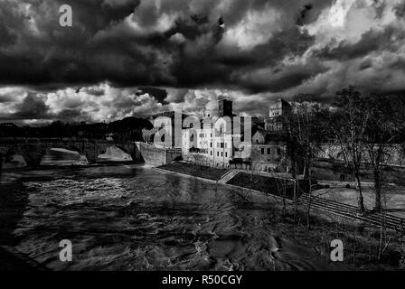 Winter in Rome. River is swollen along Tiber Island embankments under stormy clouds (Black and White) Stock Photo