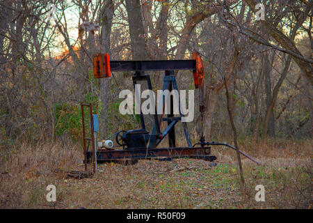 Oil Well Pump Jack in the Woods Stock Photo