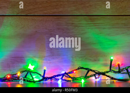 Coloured Christmas fairy lights against wooden background Stock Photo