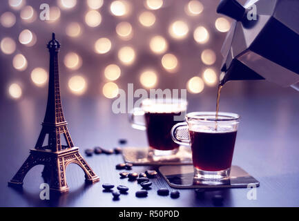 Cups of coffee and Eiffel Tower on a kitchen table with beautiful golden bokeh for background Stock Photo