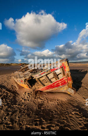 old wooden shipwreck on beach with blue sky clouds Stock Photo