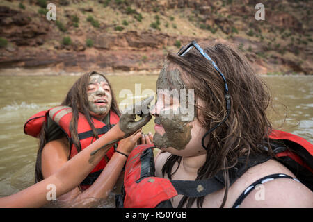 Two children playing in the river and painting mud on each others faces while on a Green river rafting trip, Desolation/Gray Canyon section, Utah, USA Stock Photo