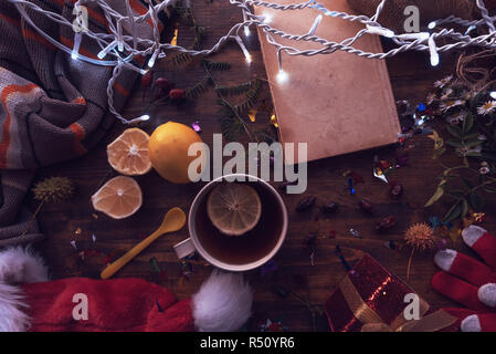 New Year and Christmas flat lay top view with Santa Claus hat, gift box and cup of tea. Happy winter holidays concept. Stock Photo