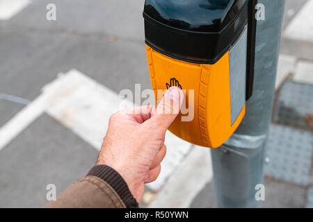 Hand pushing control button on pedestrian crossing to activate the green traffic light Stock Photo