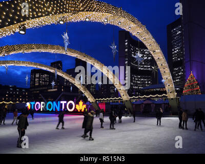 Skating rink with Christmas lights and lit Toronto sign, evening in front of Toronto's modern City Hall Stock Photo