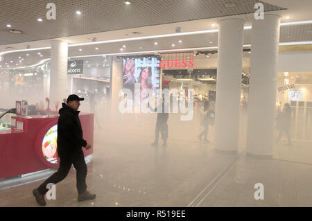 People are seen walking amidst smoke inside the Ocean Plaza shopping mall, after it was attacked with smoke grenades during the protest. Protesters assert that the owner of Ocean plaza is Russian citizen and they protested against the Russian business in Ukraine. President Poroshenko signed the law approving the decree on the introduction of martial law for 30 days in 10 regions of Ukraine which will be in effect until 26 December. Stock Photo