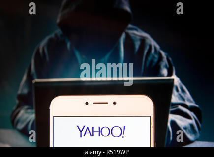 American web services provider company Yahoo! logo is seen on an Android mobile device with a figure of hacker in the background. Stock Photo