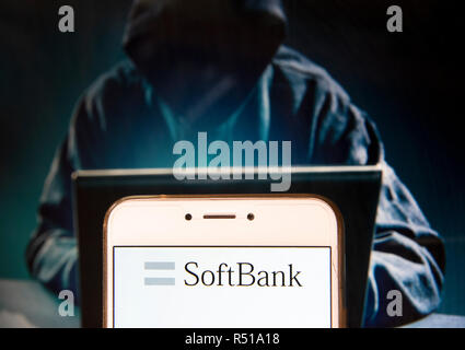 Japanese multinational holding conglomerate SoftBank logo is seen on an Android mobile device with a figure of hacker in the background. Stock Photo