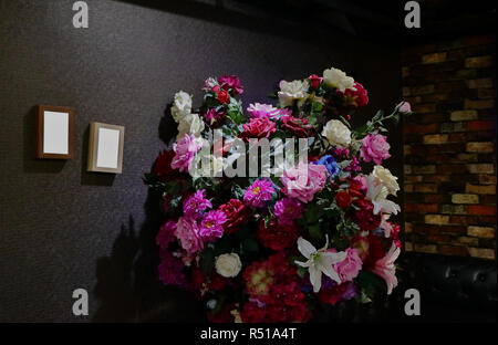 big bouquet of blooming artificial flowers and photo frames with copy space on dark wall, celebration, new year resolution concept Stock Photo