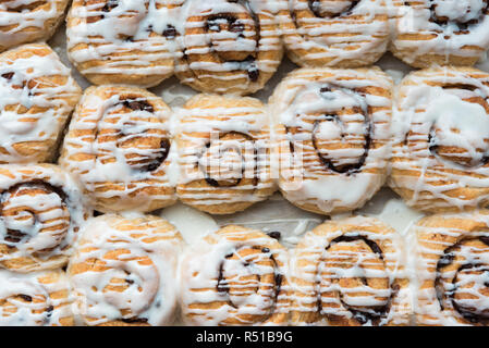 Horizontal rows of cinnamon buns in pan drizzled with vanilla frosting Stock Photo