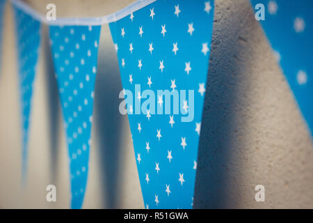 line of colorful blue party decorations flags with white stars illustration hanging from the wall Stock Photo