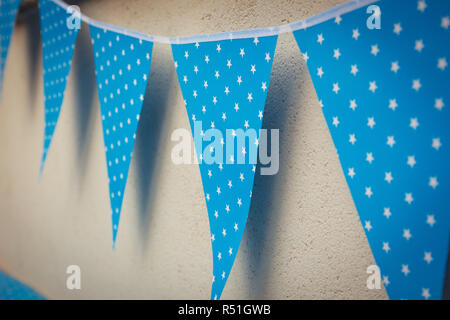 line of colorful blue party decorations flags with white stars illustration hanging from the wall Stock Photo