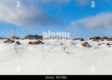 snowdrifts in the winter season, Focus on the ground near the horizon, during the blizzard and the flying snowflakes are seen in the blue sky Stock Photo