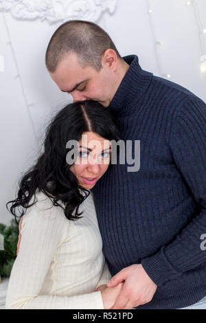 Brunette with blue eyes in a white dress with a cute young man in a black sweater Stock Photo