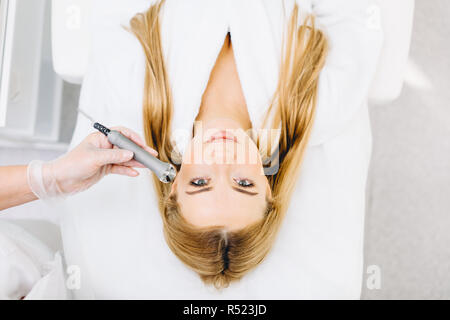 Blonde woman has ultrasonic dinamic lift massage in spa, hardware apparatus. Stock Photo