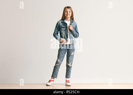 Full length portrait of cute little kid girl in stylish jeans clothes  looking at camera and smiling against white studio wall. Kids fashion  concept Stock Photo - Alamy