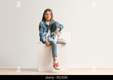 Full length portrait of cute little teen girl in stylish jeans clothes  looking at camera and smiling against white studio wall. Kids fashion  concept Stock Photo - Alamy