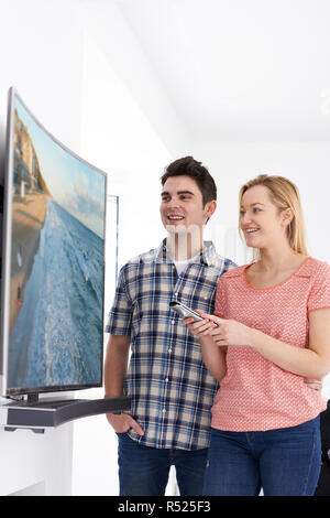 Young Couple With New Curved Screen Television At Home Stock Photo