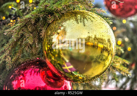 Close-up of a golden Christmas bauble covered with drops of water in a Christmas tree on a market square in an old Dutch town on a rainy day Stock Photo