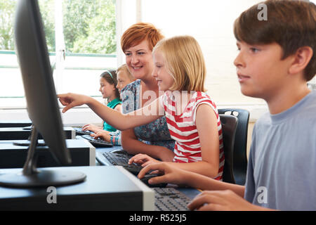 Female Elementary Pupil In Computer Class With Teacher