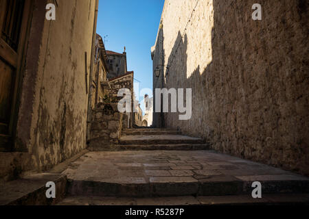 Medieval cobbled street alley with shadows on fortress wall in Dubrovnik, Croatia Stock Photo