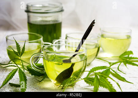 Cannabis herbal tea served in glass teacups with marijuana leaves Stock Photo