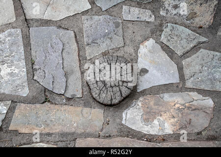 A round saw cut down of a tree between the laying of stones of various shapes. Greece Stock Photo